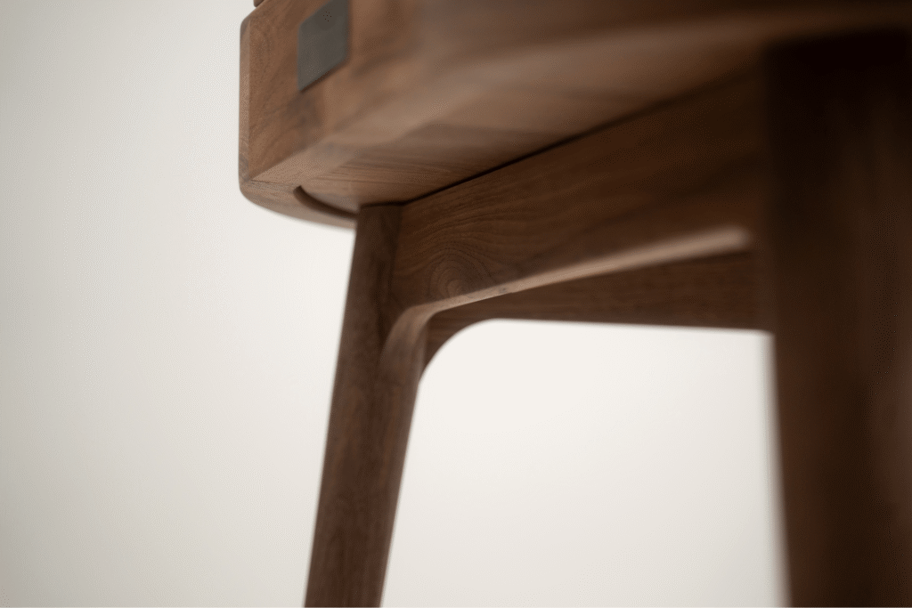 Zbliżenie na elementy kołyski norah. wykonanej z ciemnego drewna, widoczna tabliczka z logiem.